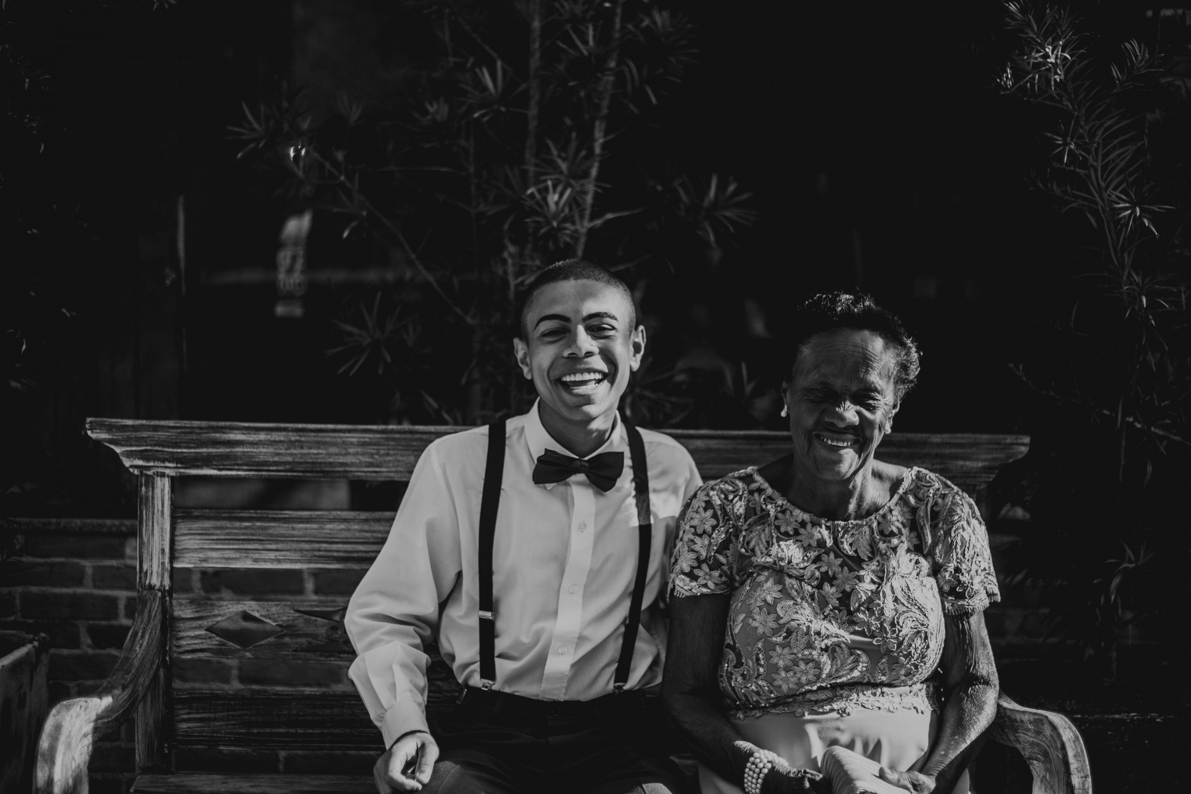 A young man and an older woman sitting on a bench smiling