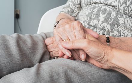 Two elderly people holding hands