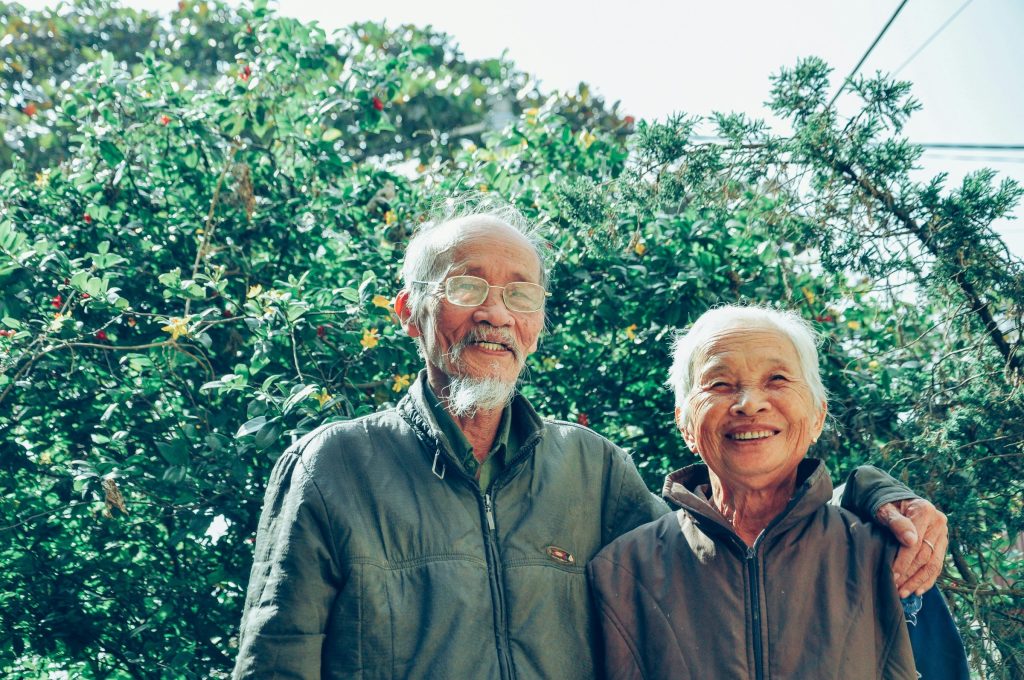 An older couple posing in front of the trees