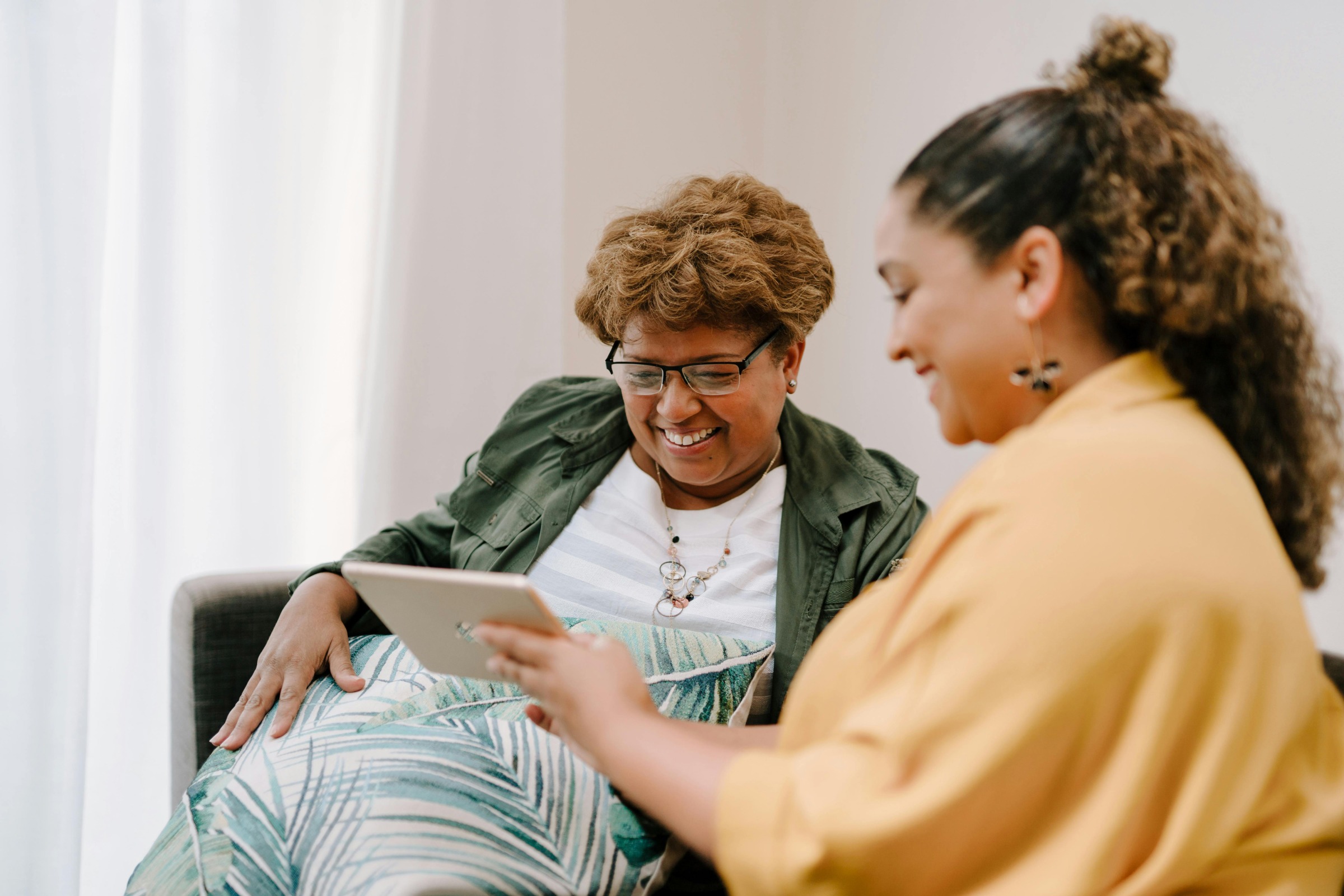 A younger woman showing an older woman something on a tablet