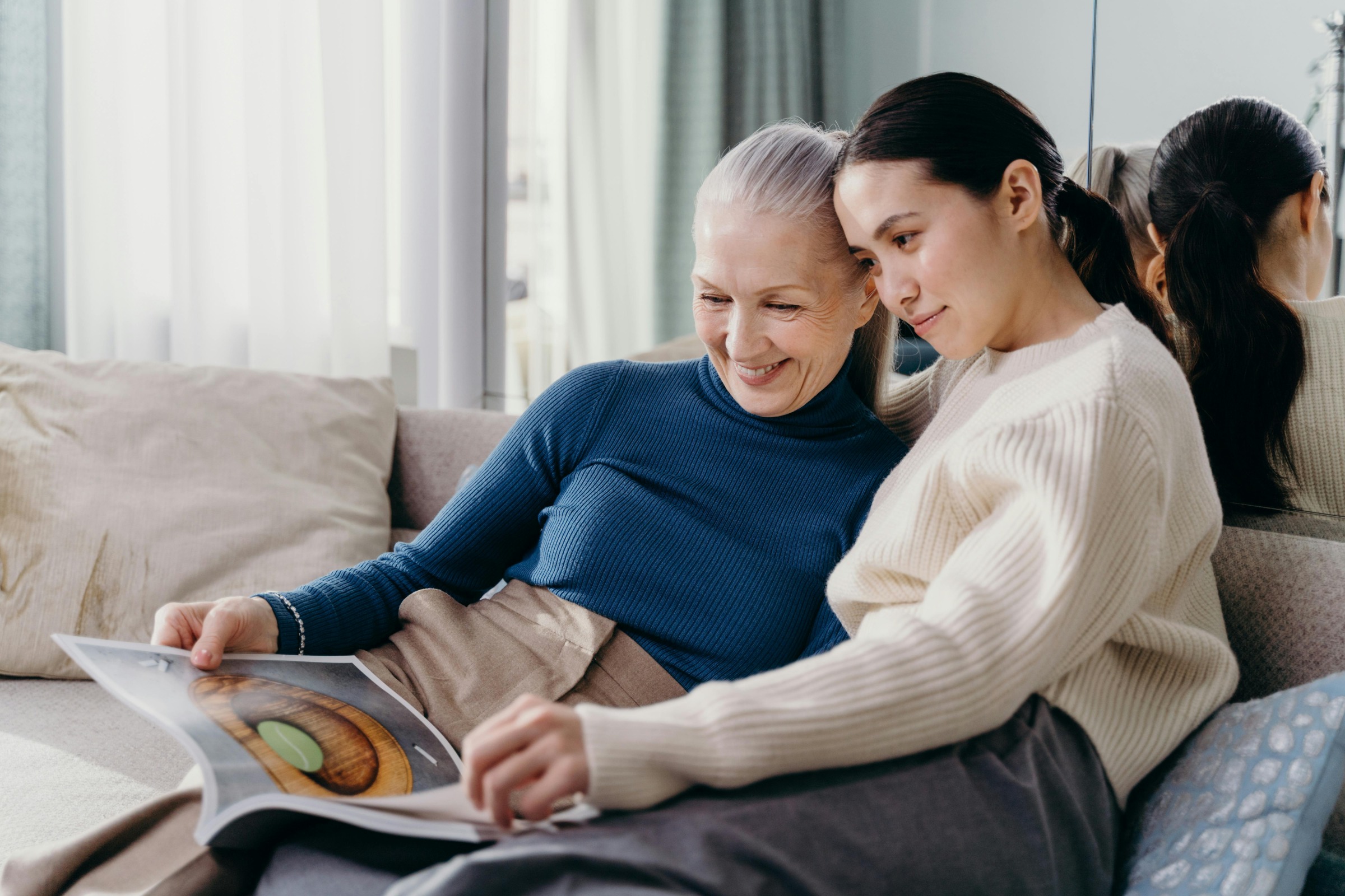 An older woman and a younger woman looking at a book together