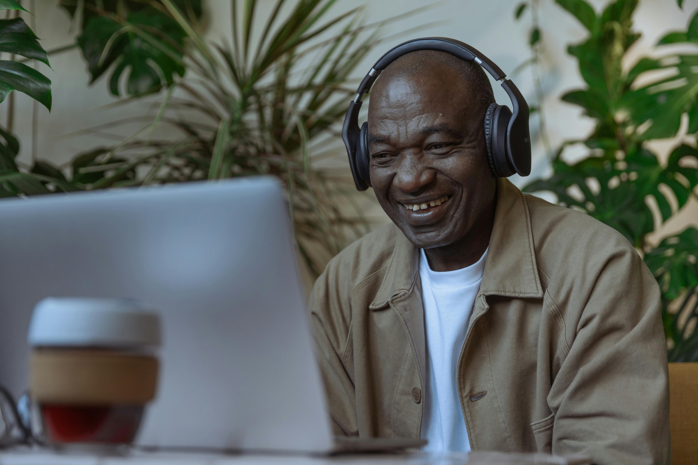 An older man wearing headphones and looking at his computer